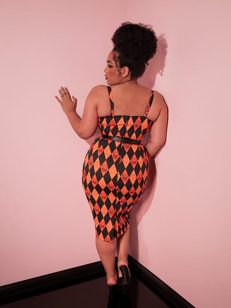 Female model facing away from the camera show off the back of the TRICK R TREAT™ Sweetheart Wiggle Dress in Halloween Harlequin Print she's modeling along with the 1" black belt.
