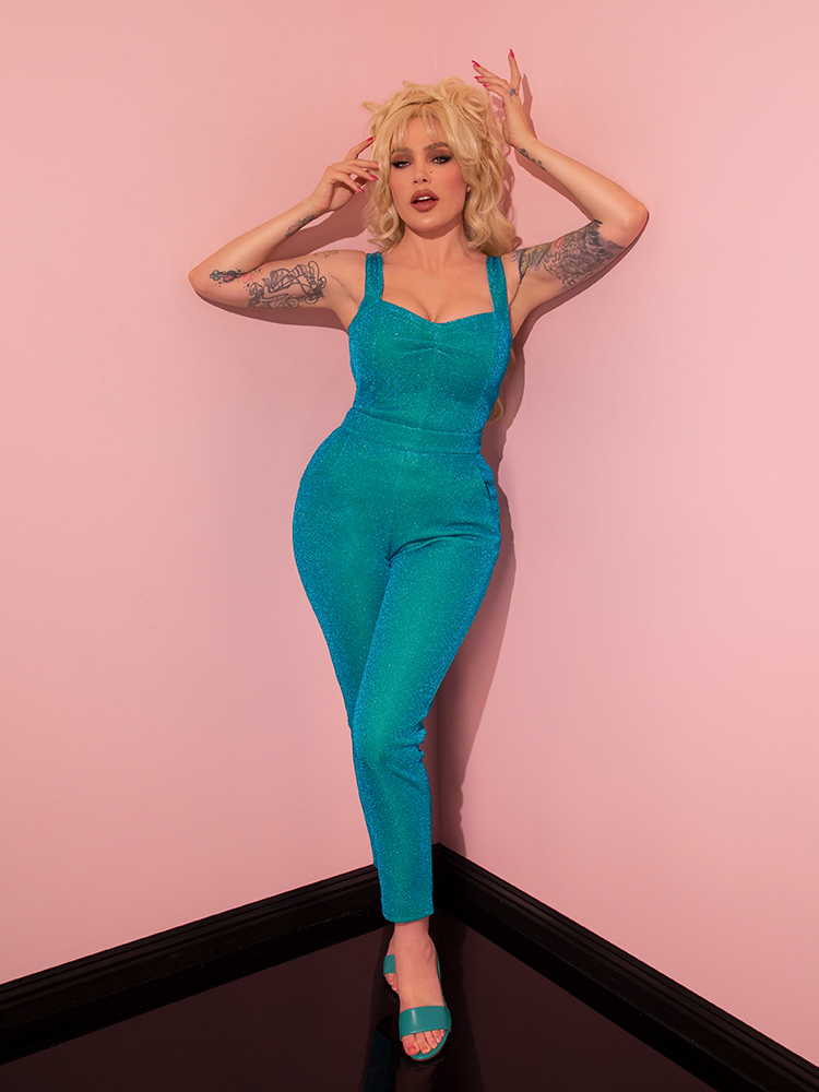 Evoking a sense of fun and seduction, the gorgeous model strikes a pose in the Turquoise Lurex Cigarette Pants from Vixen Clothing's retro line, leaving onlookers captivated.