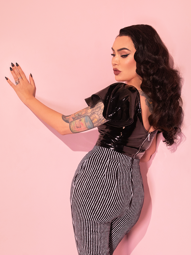 Micheline Pitt facing away from the camera to show off the back metal zipper on the Miss Kitty Babydoll Top in Black Vinyl.
