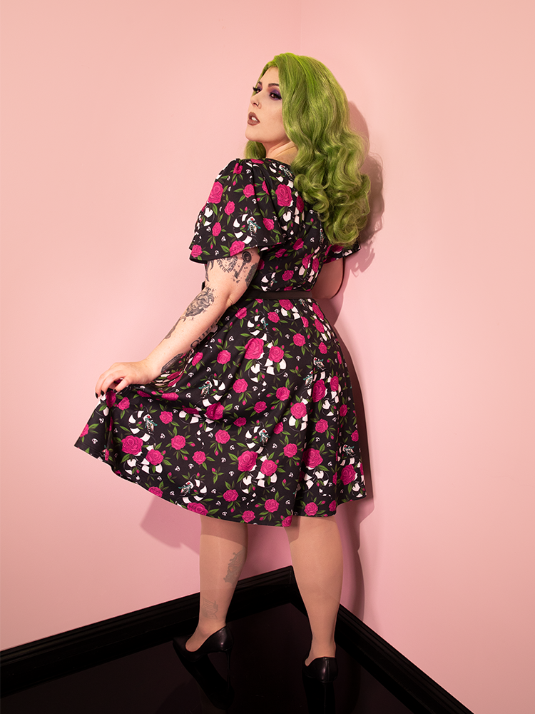Model turned away from the camera to show off the back of BEETLEJUICE™ Sandworm & Roses Swing Dress.