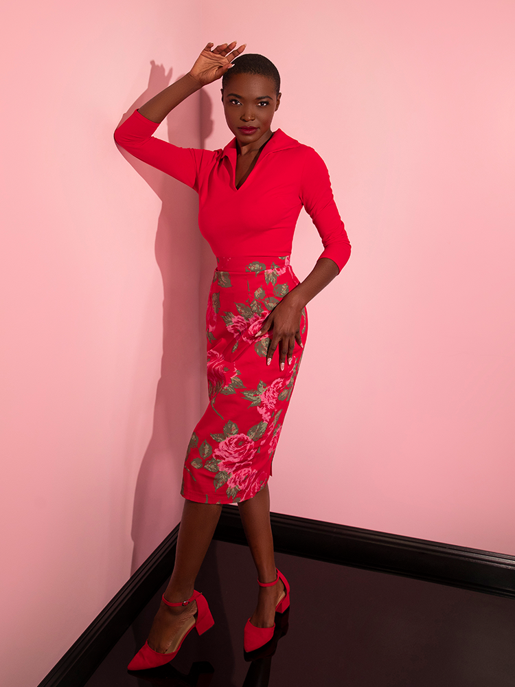 Brittany looks directly into the camera while wearing the Vixen Pencil Skirt in Vintage Red Rose Print from vintage style clothing company Vixen Clothing.