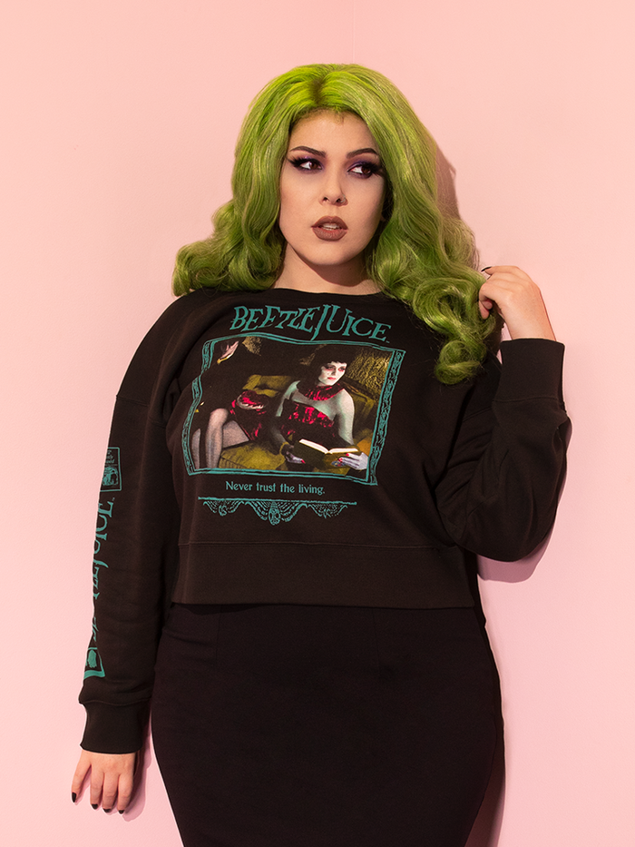 Green haired model wearing the Waiting Room Sweatshirt with a black shirt - all items from retro inspired clothing brand Vixen Clothing.