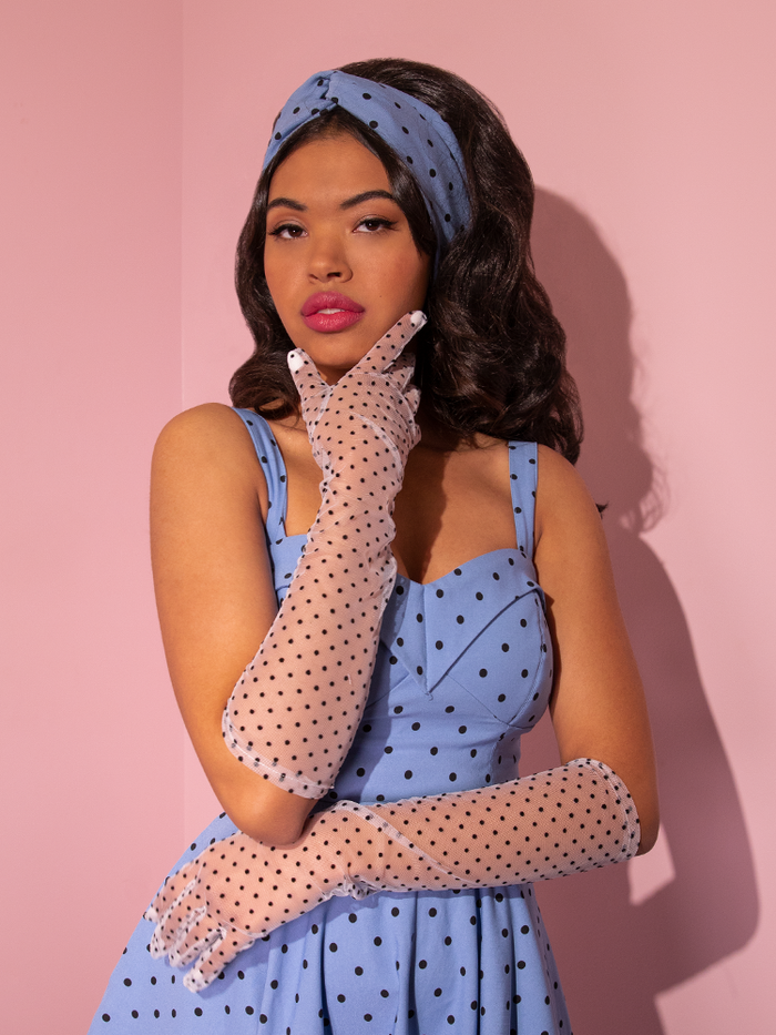 The Mesh Polka Dot Mid Length Gloves in White paired with a retro dress give off a sophisticated and classy vibe on this Vixen Clothing model. 