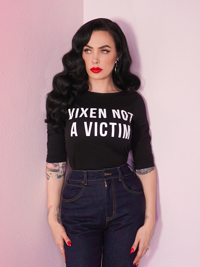 A closeup photo of Micheline Pitt looking off camera modeling the Vixen Not A Victim t-shirt by Vixen Clothing.