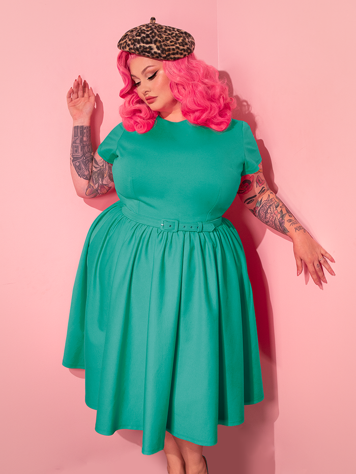 The stunning female model effortlessly transitions through poses while showcasing the Avon Swing Dress in Aquamarine from the retro fashion label Vixen Clothing.