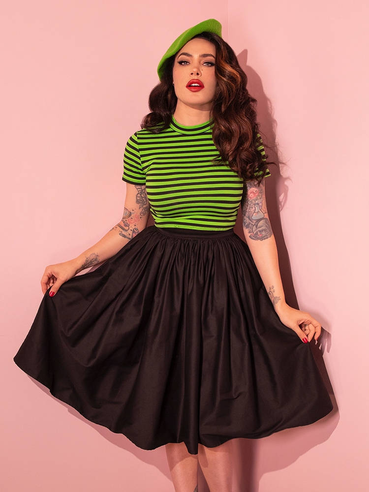 In a bold fashion statement, Micheline Pitt models the Bad Girl Crop Top in Slime Green and Black Stripes from the renowned retro clothing brand, Vixen Clothing.
