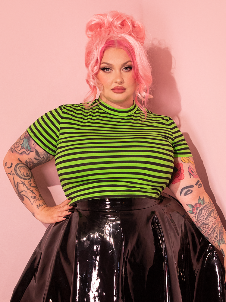 Female model wears the eye-catching Bad Girl Crop Top in Slime Green and Black Stripes, a testament to Vixen Clothing's commitment to retro style.