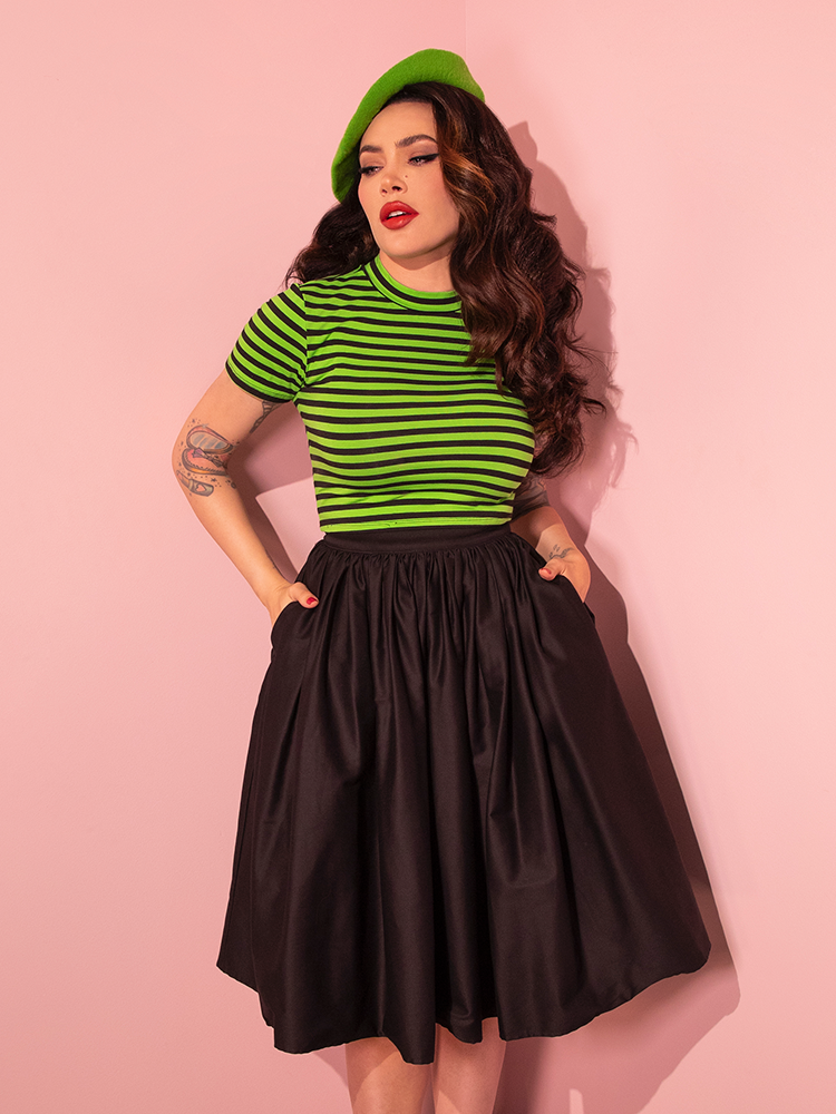 The Bad Girl Crop Top in Slime Green and Black Stripes takes center stage as Micheline Pitt embodies the spirit of retro fashion in collaboration with Vixen Clothing.
