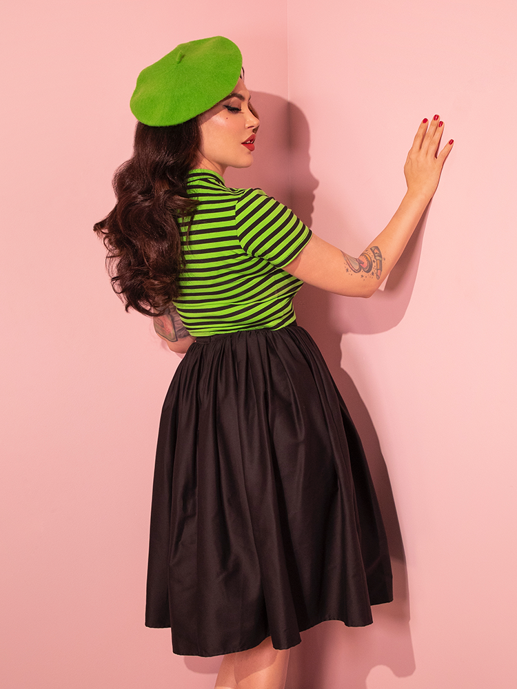 With confidence, Micheline Pitt rocks the Bad Girl Crop Top in Slime Green and Black Stripes by Vixen Clothing, embodying the brand's vintage-inspired aesthetic.