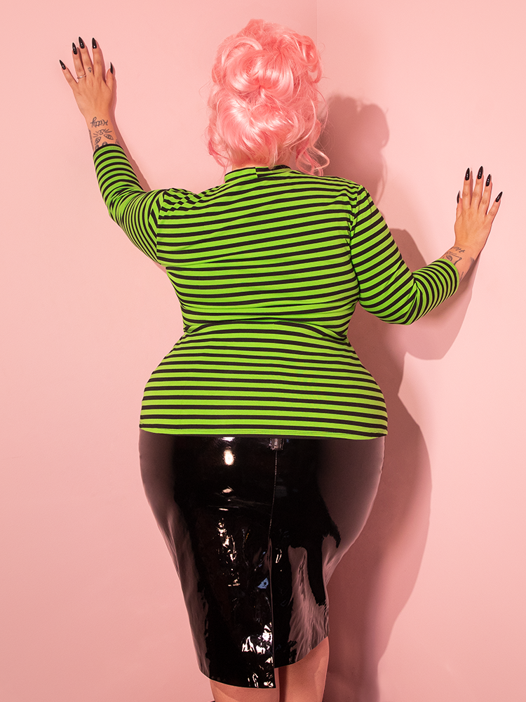 Let the beauty of a female model captivate you as she dons the Bad Girl 3/4 Sleeve Top, featuring Stunning Slime Green and Black Stripes, designed by the retro clothing brand Vixen Clothing.