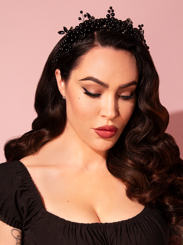 Micheline Pitt exudes timeless elegance as she complements her retro ensemble with the exquisite Rhinestone Beaded Headband in Black from Vixen Clothing, showcasing a perfect blend of vintage charm and sophistication.