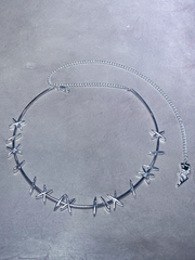 A silver vintage inspired choker with stitch detailing displayed against a pink wall, channeling dark classic Hollywood elegance.