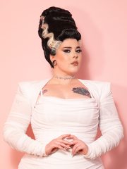 A vintage inspired white bolero with bandage-style detailing, set against a pink wall for a dramatic and classic Hollywood look.