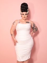 A white vintage inspired wiggle dress with corset-style bandaging, styled against a pink wall for classic Hollywood horror appeal.