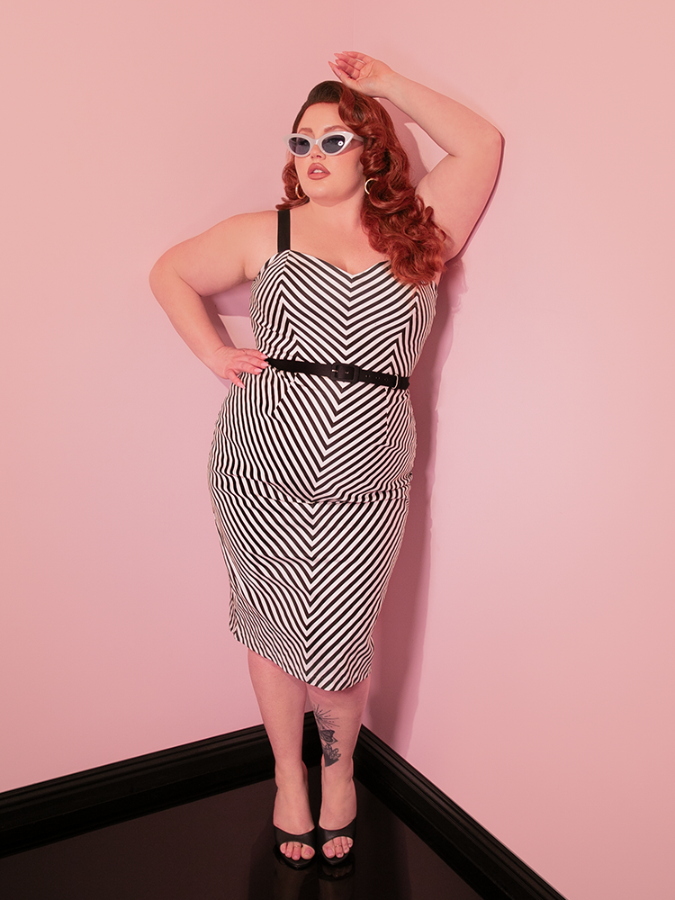 The alluring woman model reveals the Dollface Wiggle Dress, featuring classic Black and White, from the vintage house of Vixen Clothing.