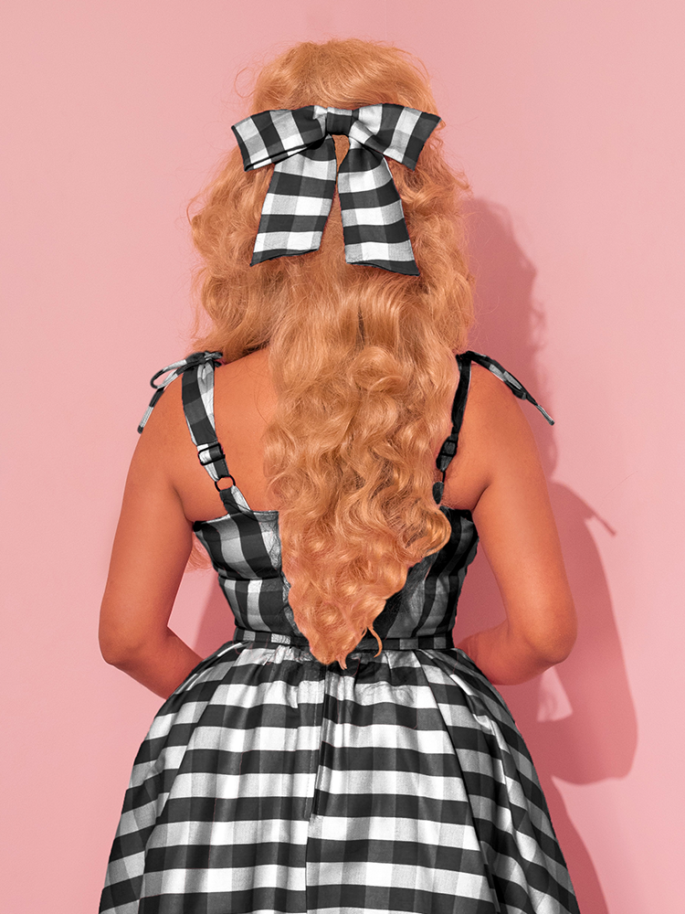 Vixen Clothing's retro masterpiece, the Dream-House Swing Dress and Matching Bow in Black Gingham, is gracefully displayed by the beautiful model, embodying timeless style.
