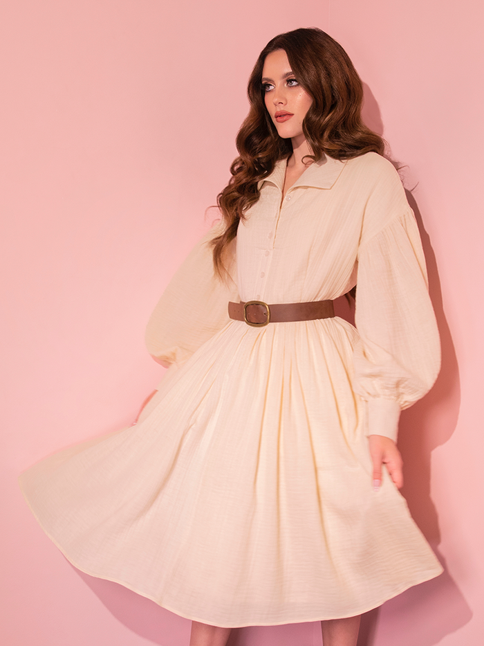 Behold the exquisite Cream Fantasy Shirtdress with Faux Leather Belt, elegantly showcased by our retro-inspired beauty, from the collection of Vixen Clothing.