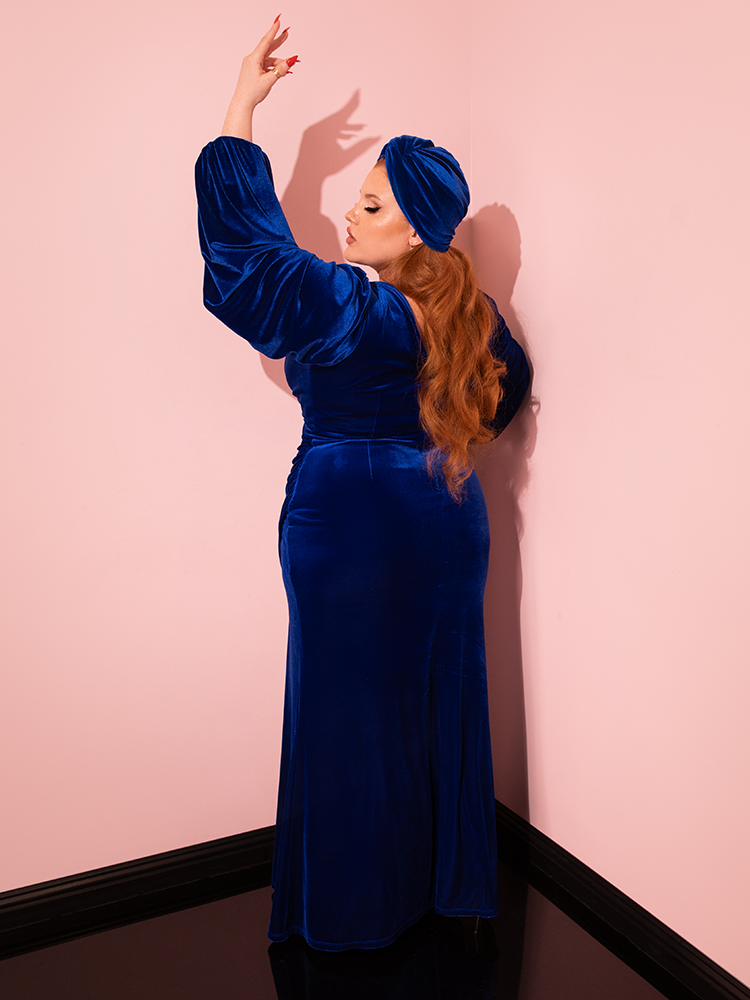 The allure of retro fashion is embodied by ginger-haired model in Vixen Clothing's Film Noir Gown and Turbanette in Blue Velvet, a masterpiece of retro clothing design.