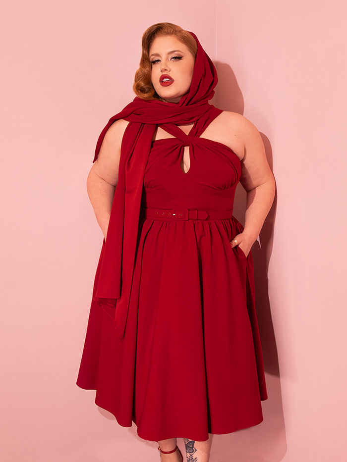 Striking a pose, beautiful retro models showcase the Golden Era Swing Dress and Scarf in Ruby Red from Vixen Clothing.