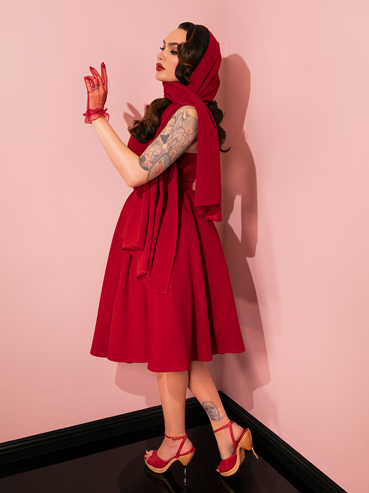 Retro charm takes center stage as gorgeous models strike poses to showcase the timeless appeal of the Golden Era Swing Dress and Scarf in Ruby Red from Vixen Clothing.