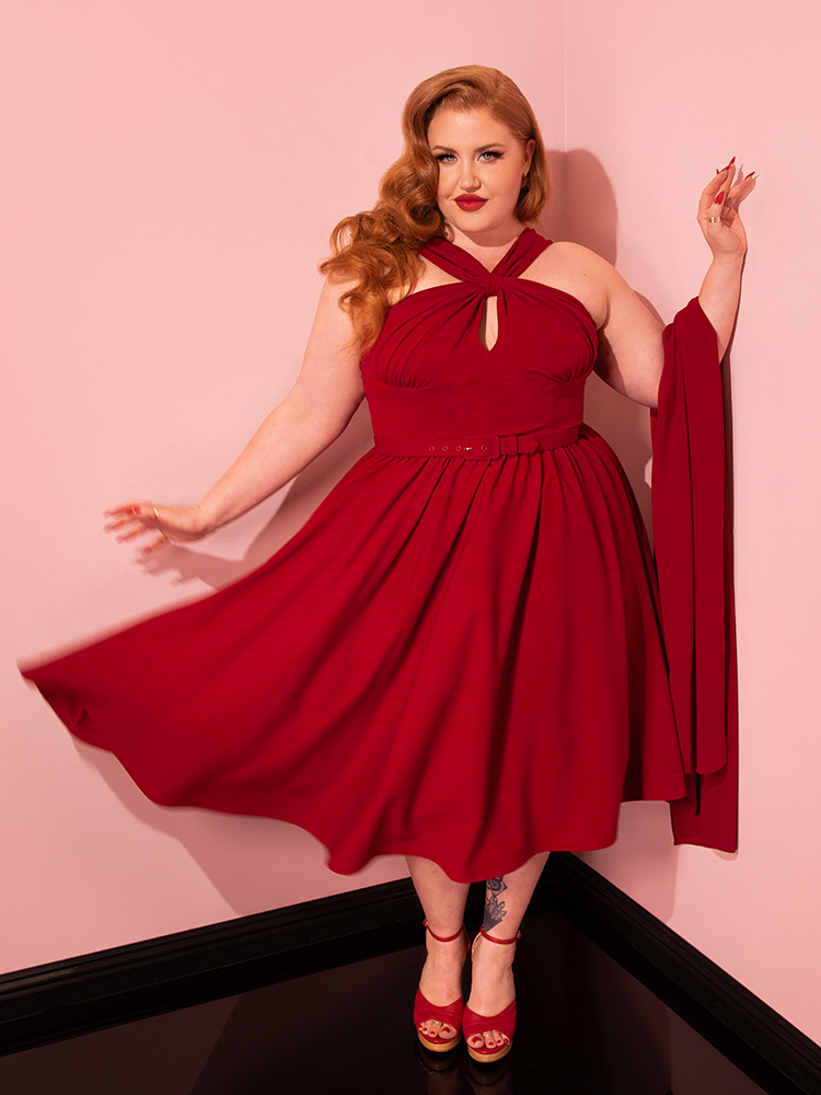 In a glamorous display, lovely models highlight the elegance of the Golden Era Swing Dress and Scarf in Ruby Red from Vixen Clothing.