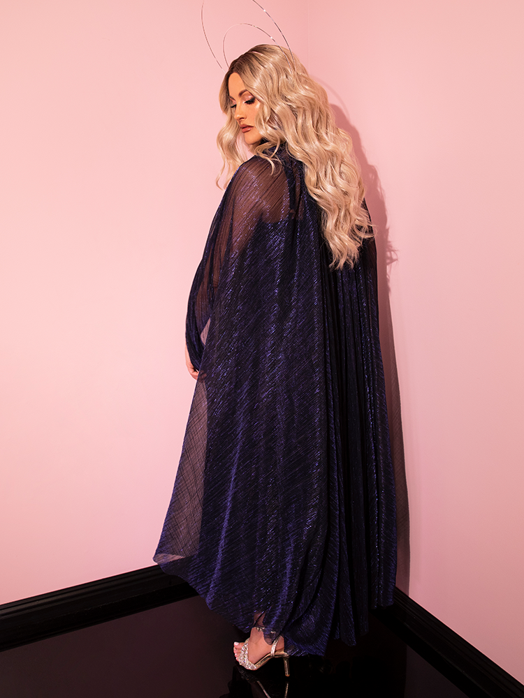 Retro fashion is redefined as the LABYRINTH™ Jareth Gown and Matching Cape in Midnight Blue shine brilliantly on this stunning model from Vixen Clothing.