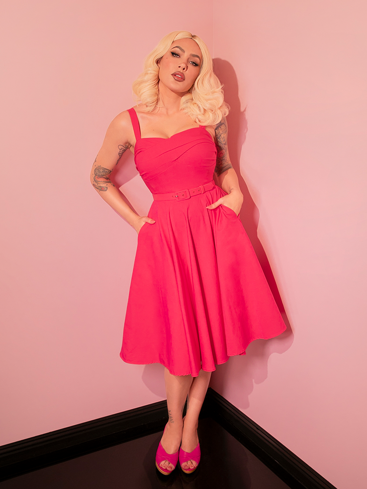 Featuring a flirty, full swing skirt, this dress takes inspiration from the iconic silhouettes of retro dresses, updated with a hot pink hue that demands attention.