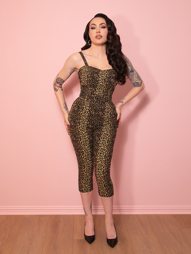 A chic pair of leopard print Capri Pants with vintage influence, showcased against a pink wall.