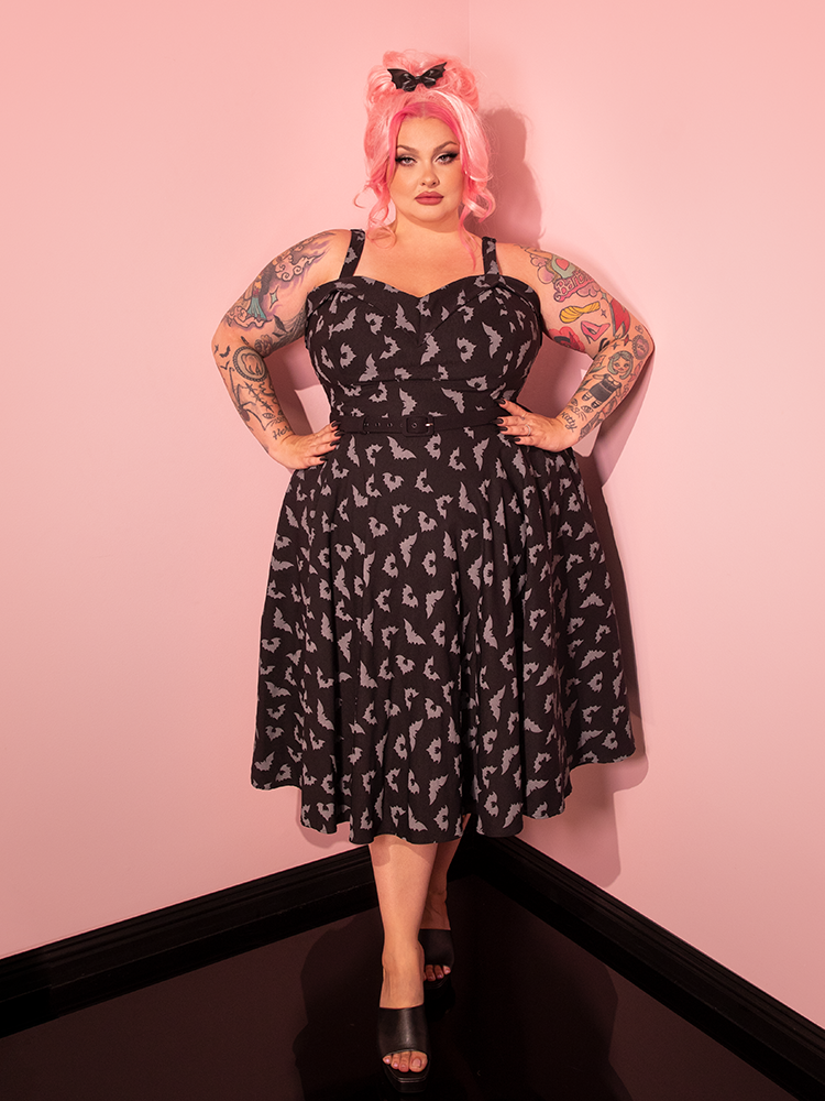 Behold the Maneater Swing Dress in the Glow in the Dark Bat Print, beautifully worn by a stunning female model, proudly presented by Vixen Clothing, the vintage-inspired retro dress brand.