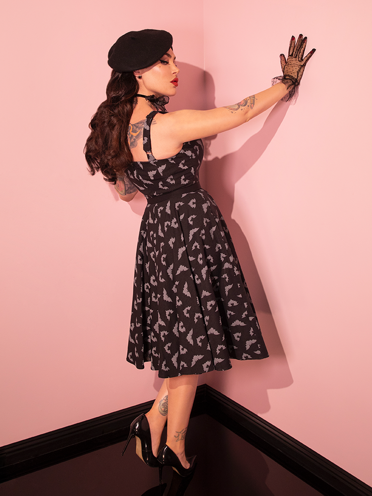 Experience the allure of yesteryears' fashion with our beautiful female model showcasing the Maneater Swing Dress in the Glow in the Dark Bat Print, expertly crafted by Vixen Clothing, the vintage-inspired retro dress brand.