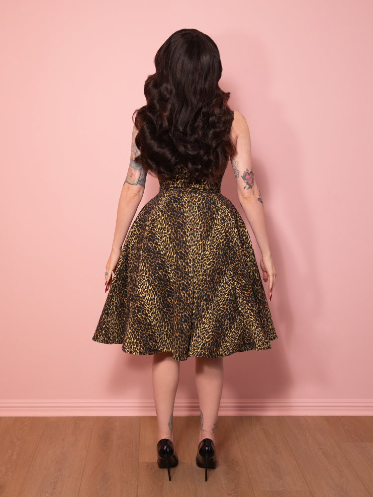 The leopard print Maneater Swing Dress radiating old Hollywood charm, displayed before a pink backdrop.