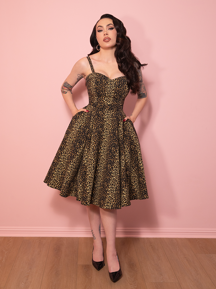 The Maneater Swing Dress in leopard print styled with sophistication, highlighted against a soft pink background.