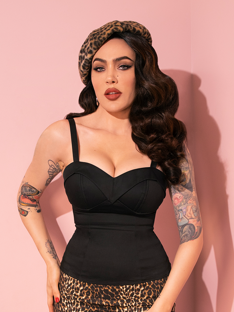 Gracefully poised, Micheline Pitt models the retro-inspired Maneater Top in Black from Vixen Clothing, showcasing its versatility with a range of poses.