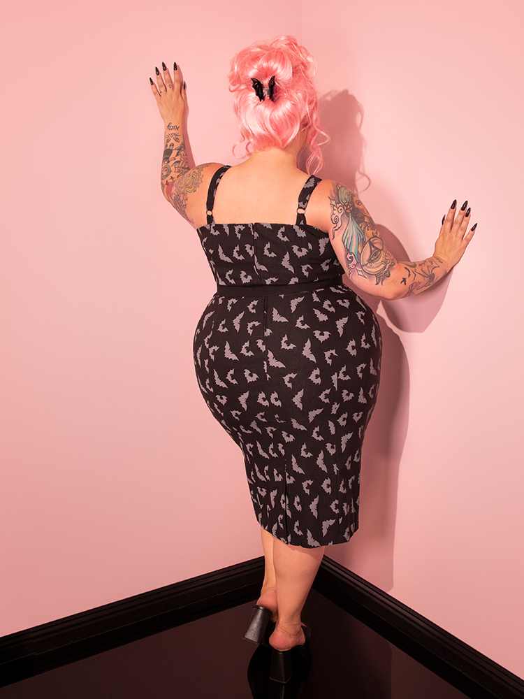 Let the allure of our beautifully styled model captivate you as she dons the Maneater Wiggle Dress, featuring the Black Glow in the Dark Bat Print, designed by Vixen Clothing, the trusted retro dress and clothing brand.