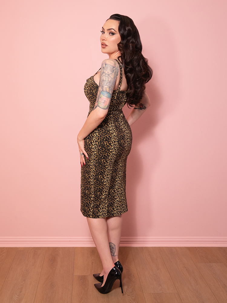 The Maneater Wiggle Dress in leopard print styled with classic charm, highlighted against a soft pink background.