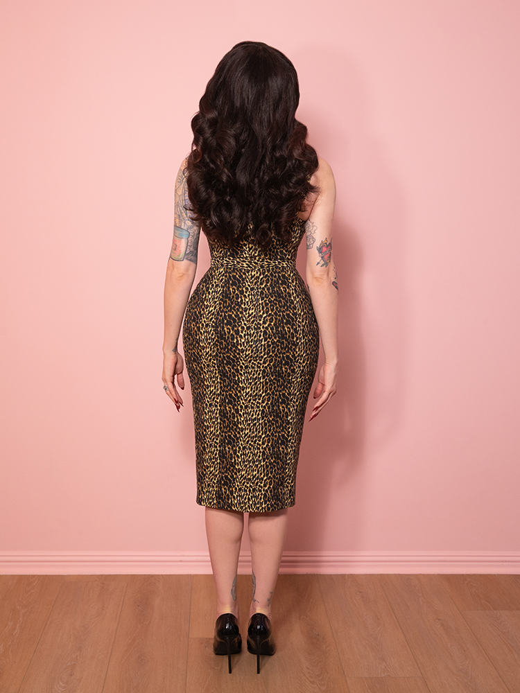 A vintage inspired leopard print Maneater Wiggle Dress with sultry Hollywood flair, set before a pink wall.