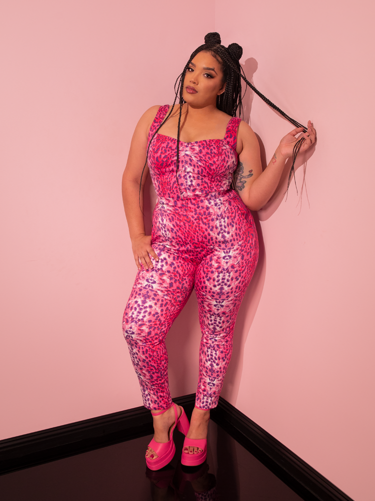 Evoking the charm of yesteryears, a breathtaking female model exudes allure while modeling the Pink Leopard Print Cigarette Pants, a stunning creation by Vixen Clothing, a beloved retro clothing brand.