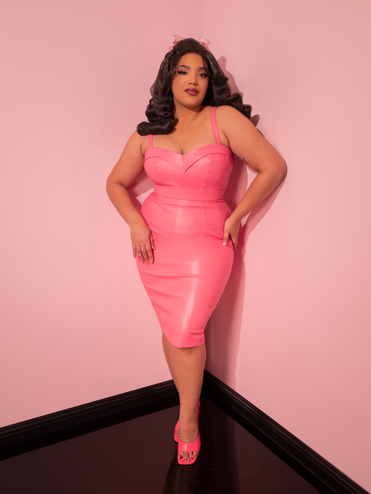 Capture the magic of vintage allure as the stunning model graces the scene in the all new Bad Girl Maneater Top, a remarkable piece crafted in Flamingo Pink Vegan Leather by the iconic retro dress and vintage clothing brand, Vixen Clothing.