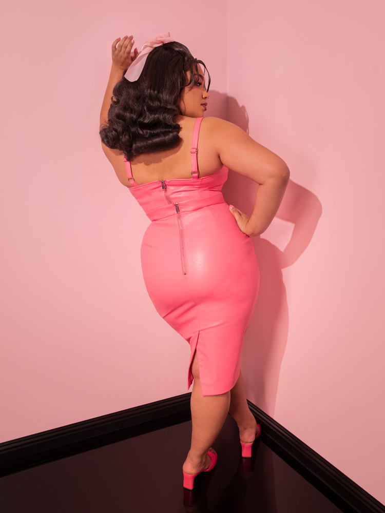 Step into a bygone era of glamour with the sultry model, showcasing the Flamingo Pink Vegan Leather Bad Girl Pencil Skirt - a nostalgic creation by Vixen Clothing, the ultimate destination for vintage dresses.