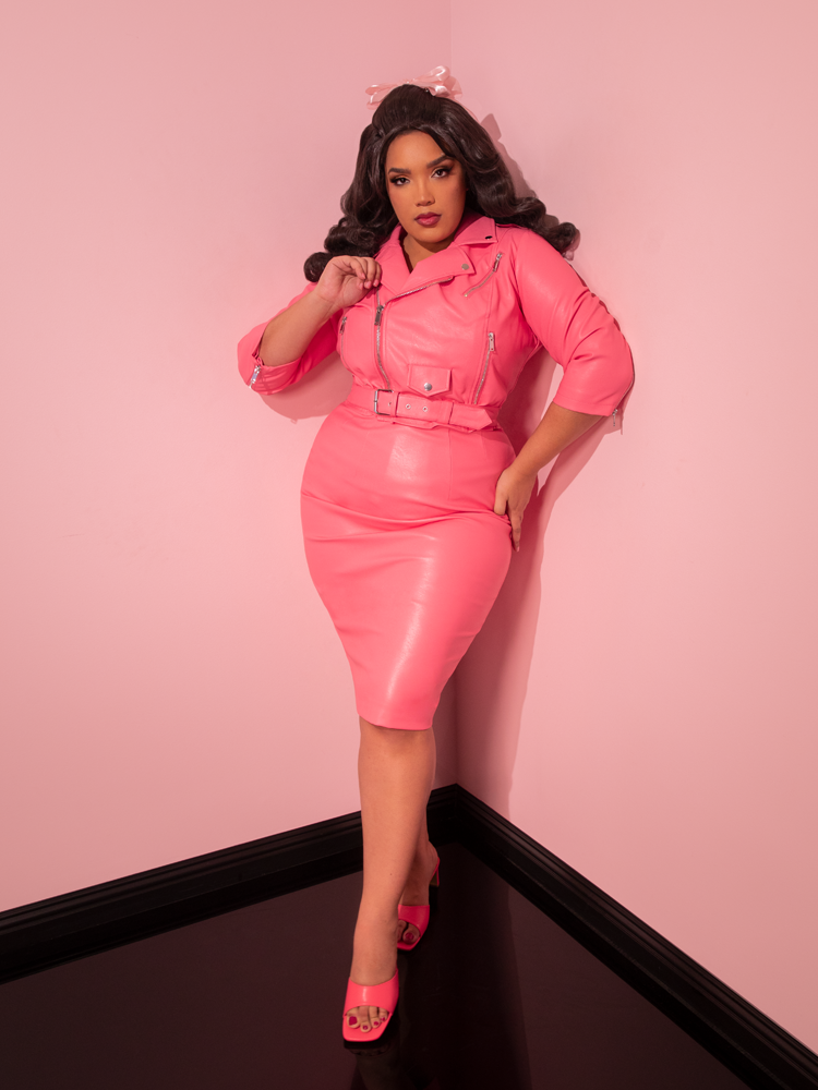 Admire the vintage grace of the sultry model, captivating all with the Bad Girl Pencil Skirt from Vixen Clothing - a retro-inspired delight in Flamingo Pink Vegan Leather.