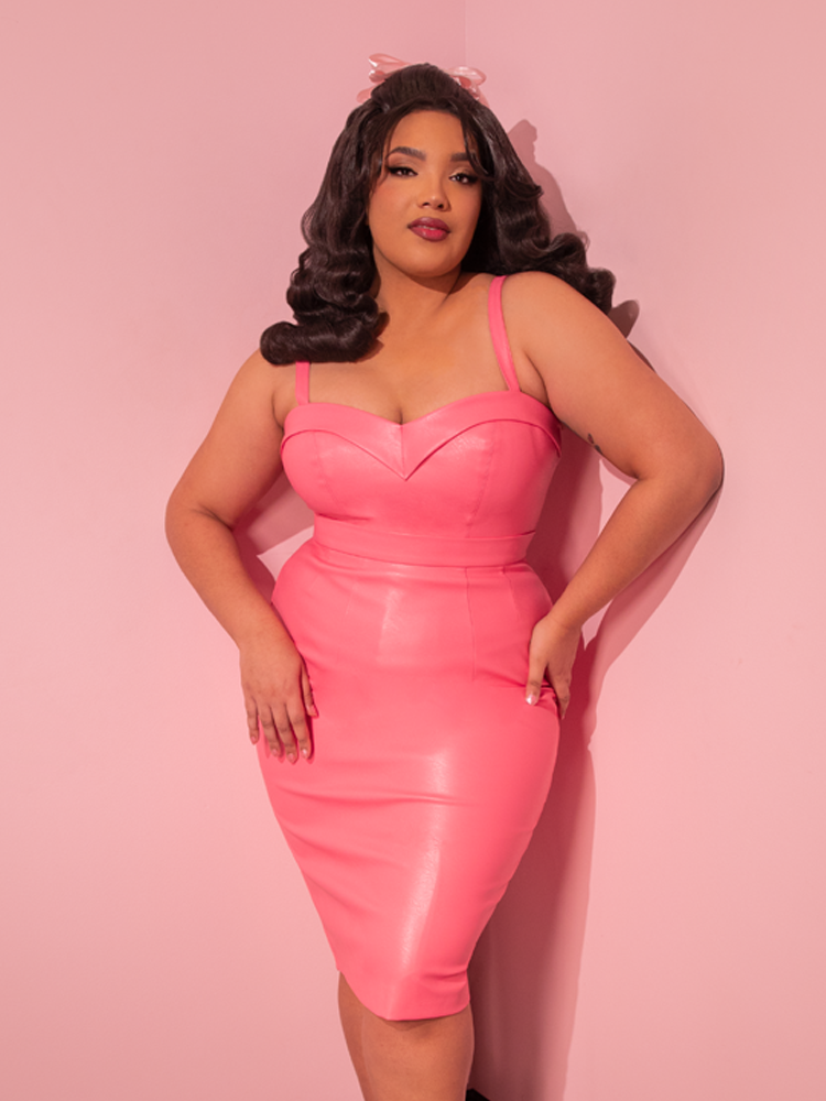 Delight in the sight of the ravishing model, embodying the essence of retro fashion with the all new Bad Girl Maneater Top in Flamingo Pink Vegan Leather, a prized possession from the renowned vintage clothing brand, Vixen Clothing.