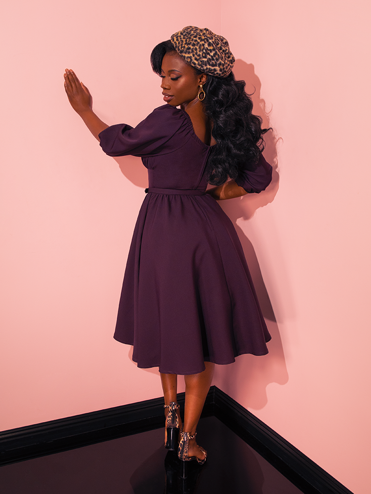 Celebrating the playful side of fashion, female vintage models strike fun and flirty poses in Vixen Clothing's Vacation Dress in Plum, a testament to the brand's dedication to crafting unique retro clothing.