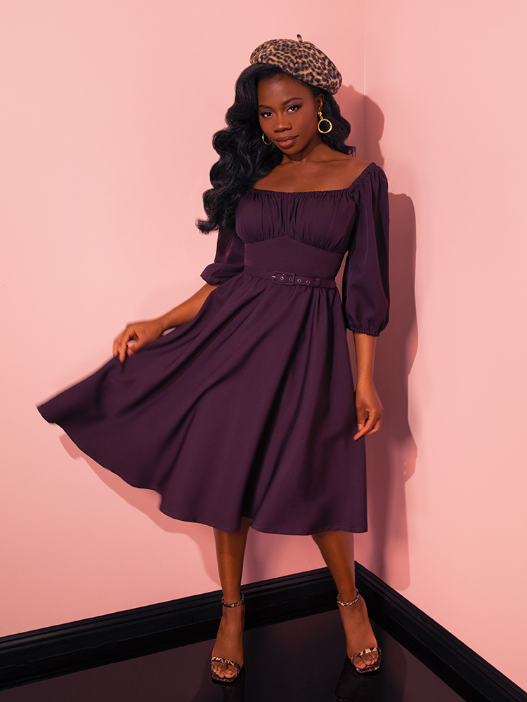 Radiating joy and flirtatious vibes, the female vintage models don the Vacation Dress in Plum from Vixen Clothing, celebrating the brand's expertise in crafting delightful retro dress styles.