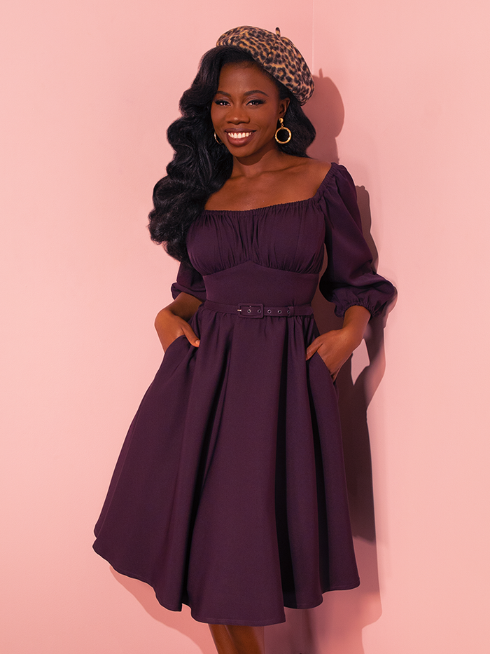 Vintage models exude fun and flirtation as they strike poses in Vixen Clothing's Vacation Dress in Plum, showcasing the playful charm of this retro dress.