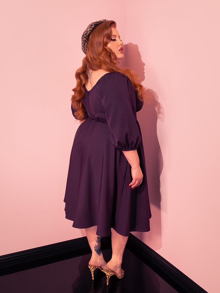 The Vacation Dress in Plum becomes a symbol of fun and flirtation as female vintage models strike poses, embodying the lively spirit of Vixen Clothing's retro dress collection.