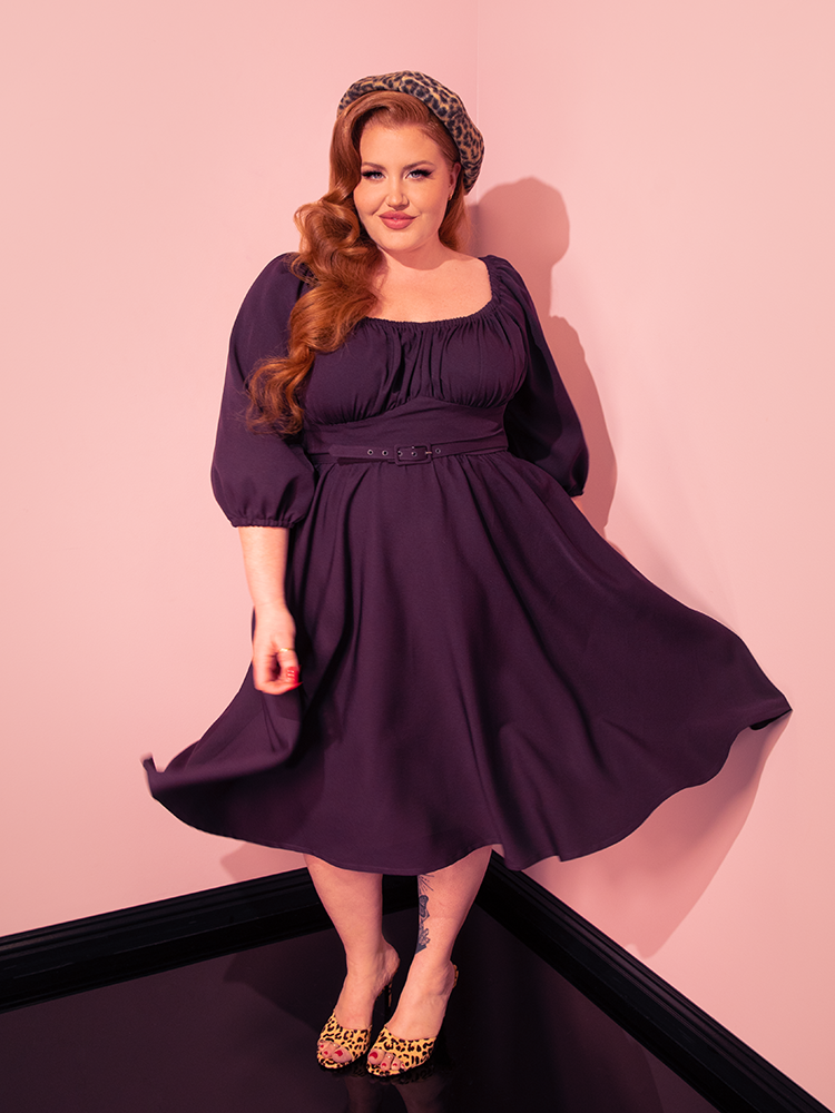 The Vacation Dress in Plum steals the spotlight as female vintage models strike poses, infusing a sense of fun and flirtation into the scene, thanks to Vixen Clothing's signature retro dress design.