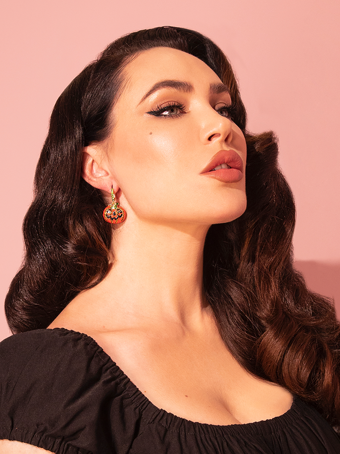 Micheline Pitt poses in a profile style position to show off the Jack-O Lantern Hoop Earrings in Gold.