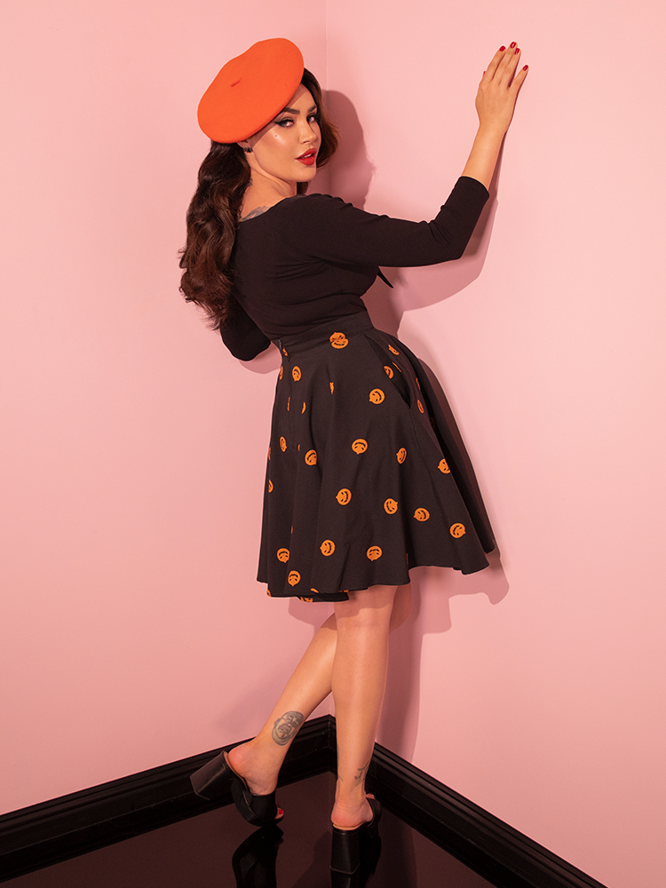 With a touch of nostalgia, the beautiful model highlights the Black Pumpkin King Maneater Skater Skirt from the renowned vintage clothing brand Vixen Clothing, truly embracing the spirit of retro fashion.