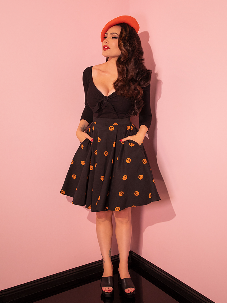 An epitome of vintage glamour, the beautiful model showcases the Black Pumpkin King Maneater Skater Skirt, an iconic piece from Vixen Clothing's retro collection.