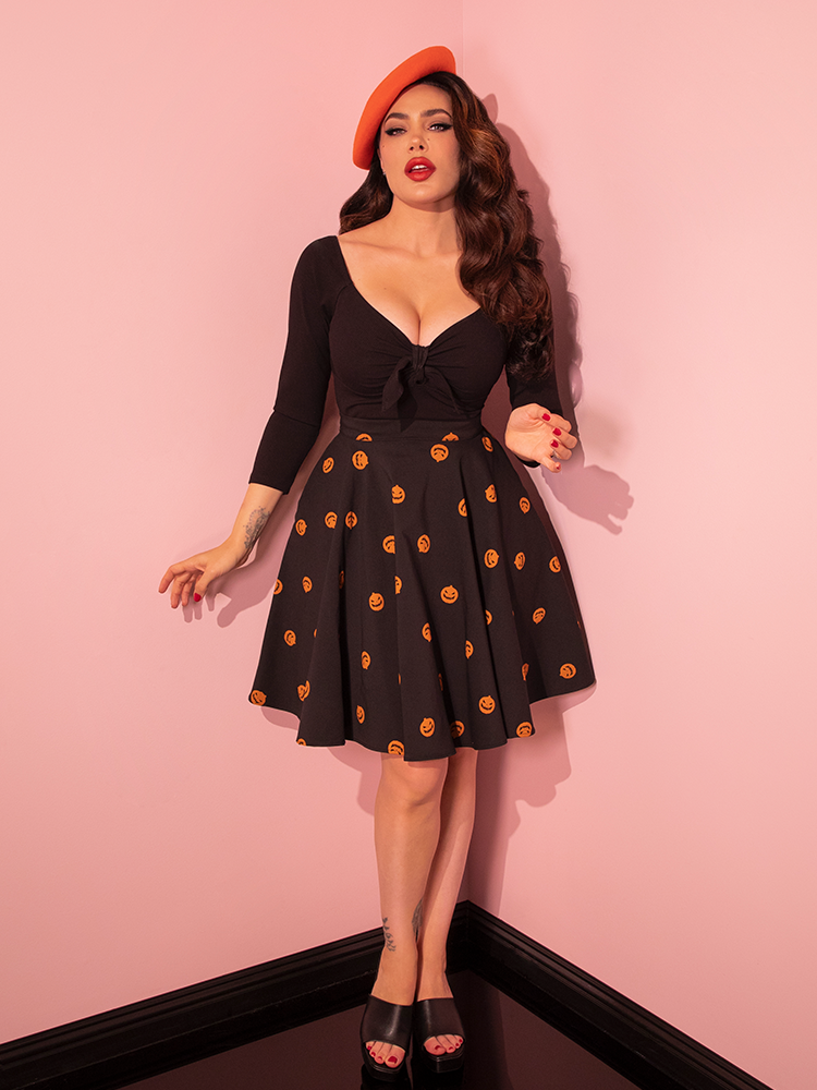 In a striking display of vintage elegance, the retro model dons the Black Pumpkin King Maneater Skater Skirt, handpicked from the exquisite range offered by Vixen Clothing, the ultimate destination for retro dress enthusiasts.
